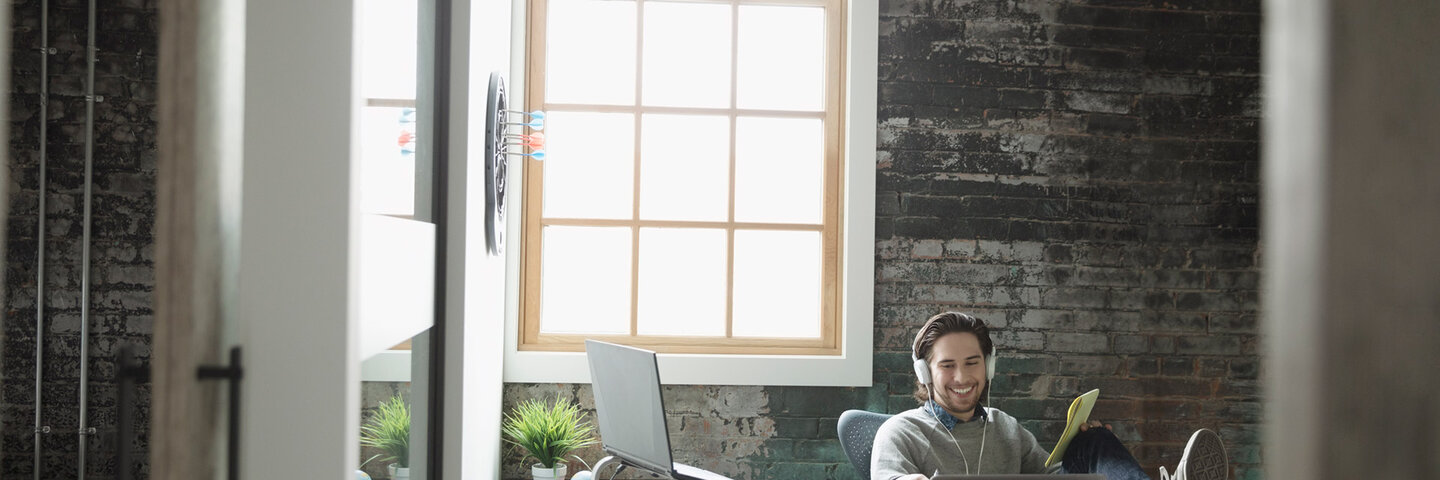 Music producer listening to headphones in office