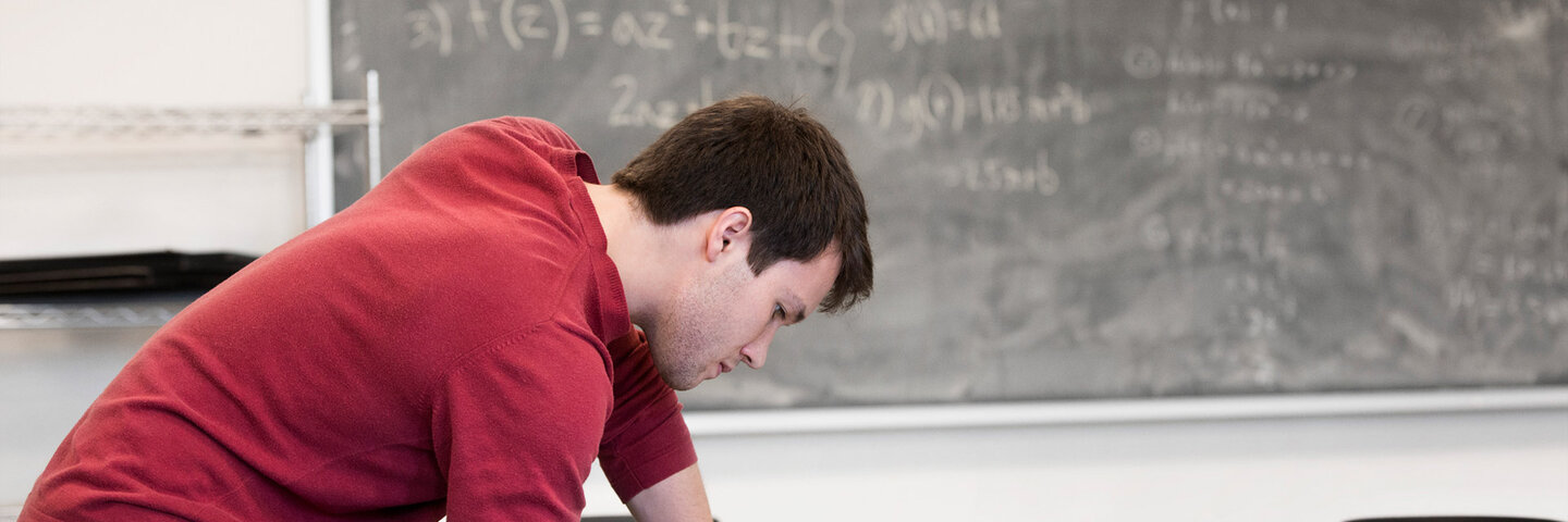 Caucasian student writing at table in classroom
