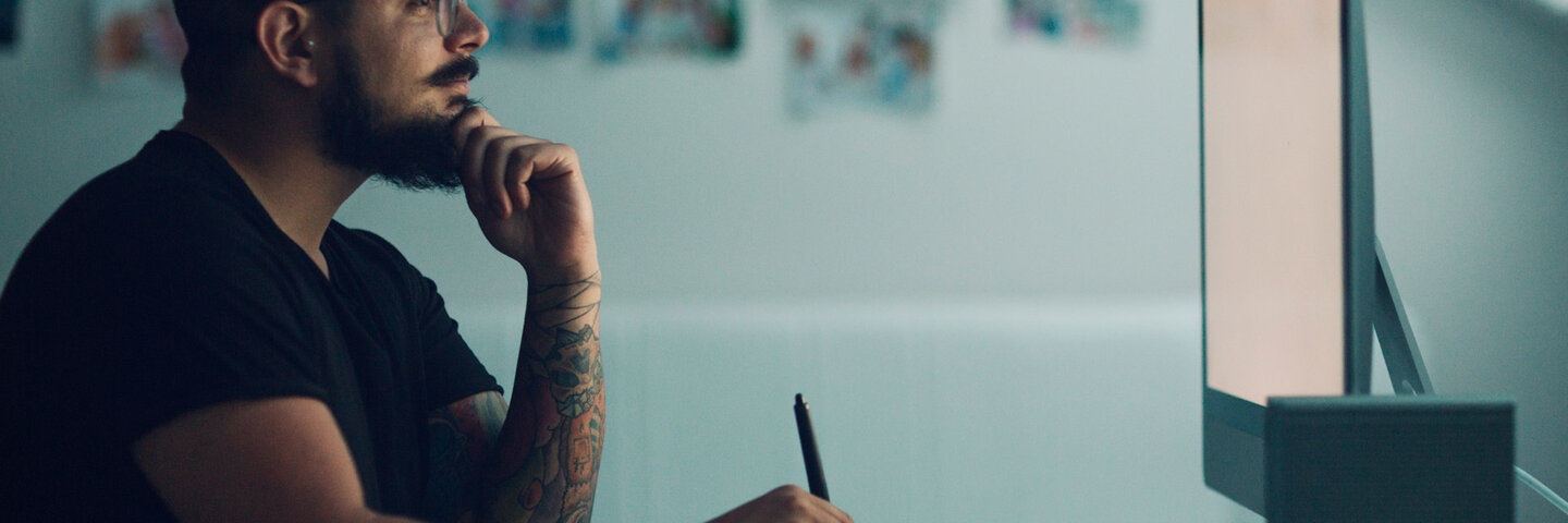 Graphic Illustrator or designer working in his own office, drawing with digitized pen.