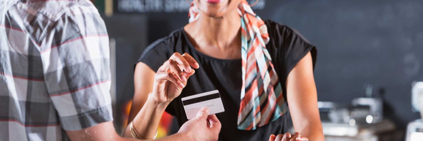 Coffee shop worker taking a BruinCard payment from a customer.