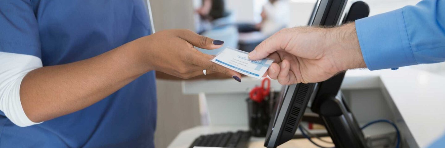 Patient handing health insurance card to nurse