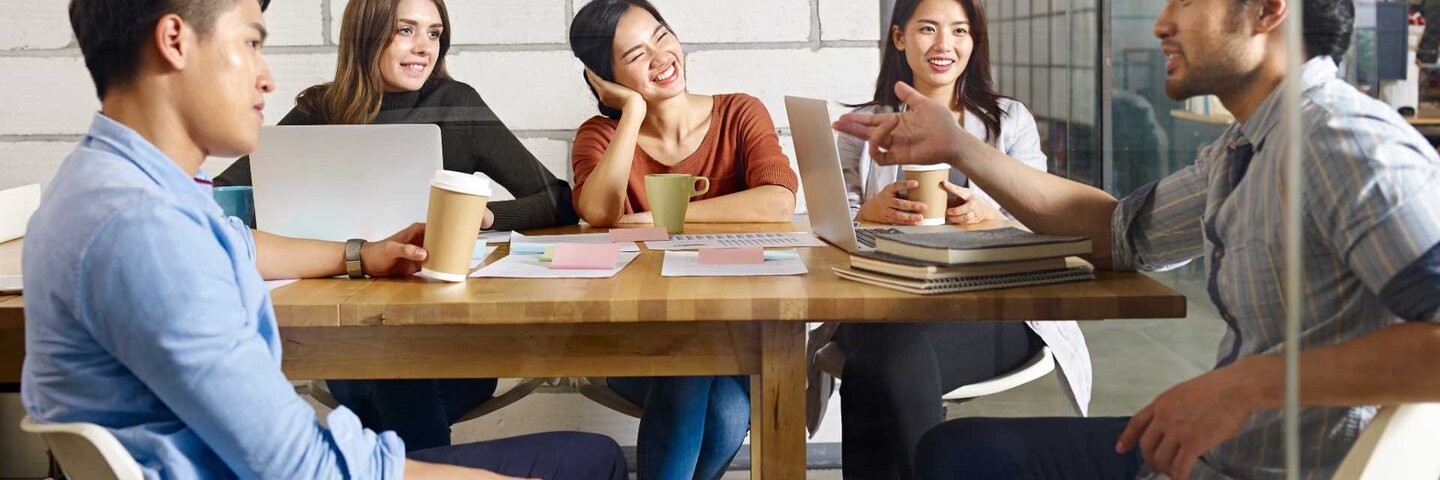 A team of multinational people discussing business in glass meeting room.