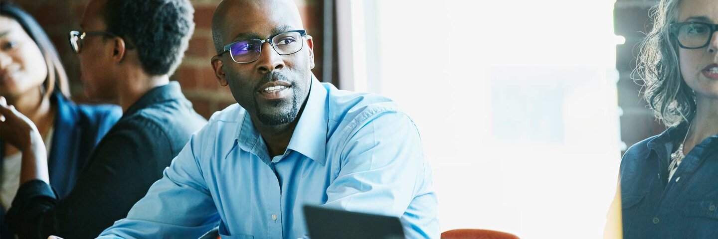 Coworkers in discussion during team meeting in office conference room
