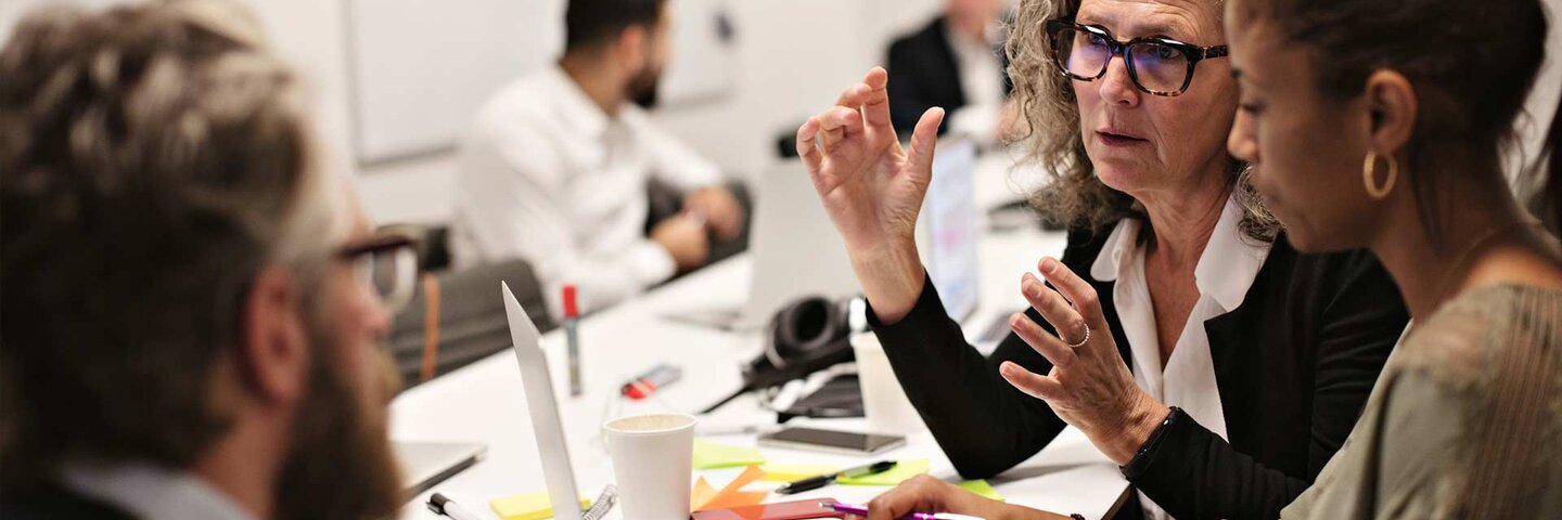 Two women with one man at laptop in meeting