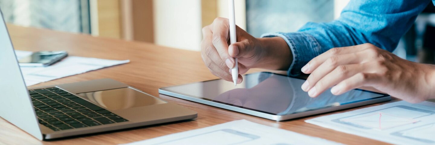 A designer working on UX design on a tablet and laptop.