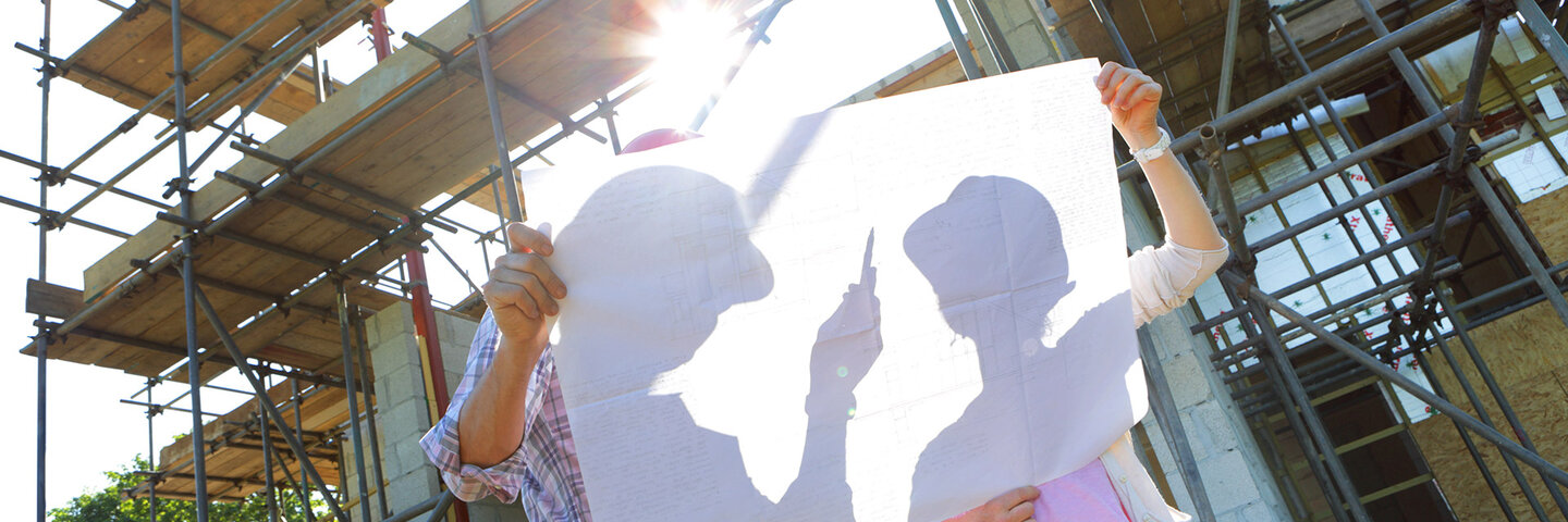 Two people reviewing blueprints at a construction site