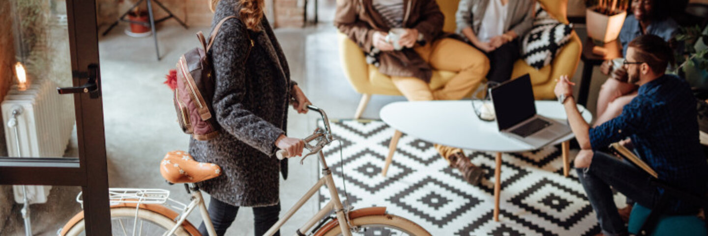 young woman walking her bicycle into her place of work