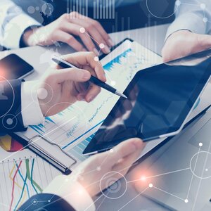 hands holding an ipad and pointing to data with a pen