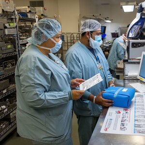Two medical professionals in protective gear handling medical package